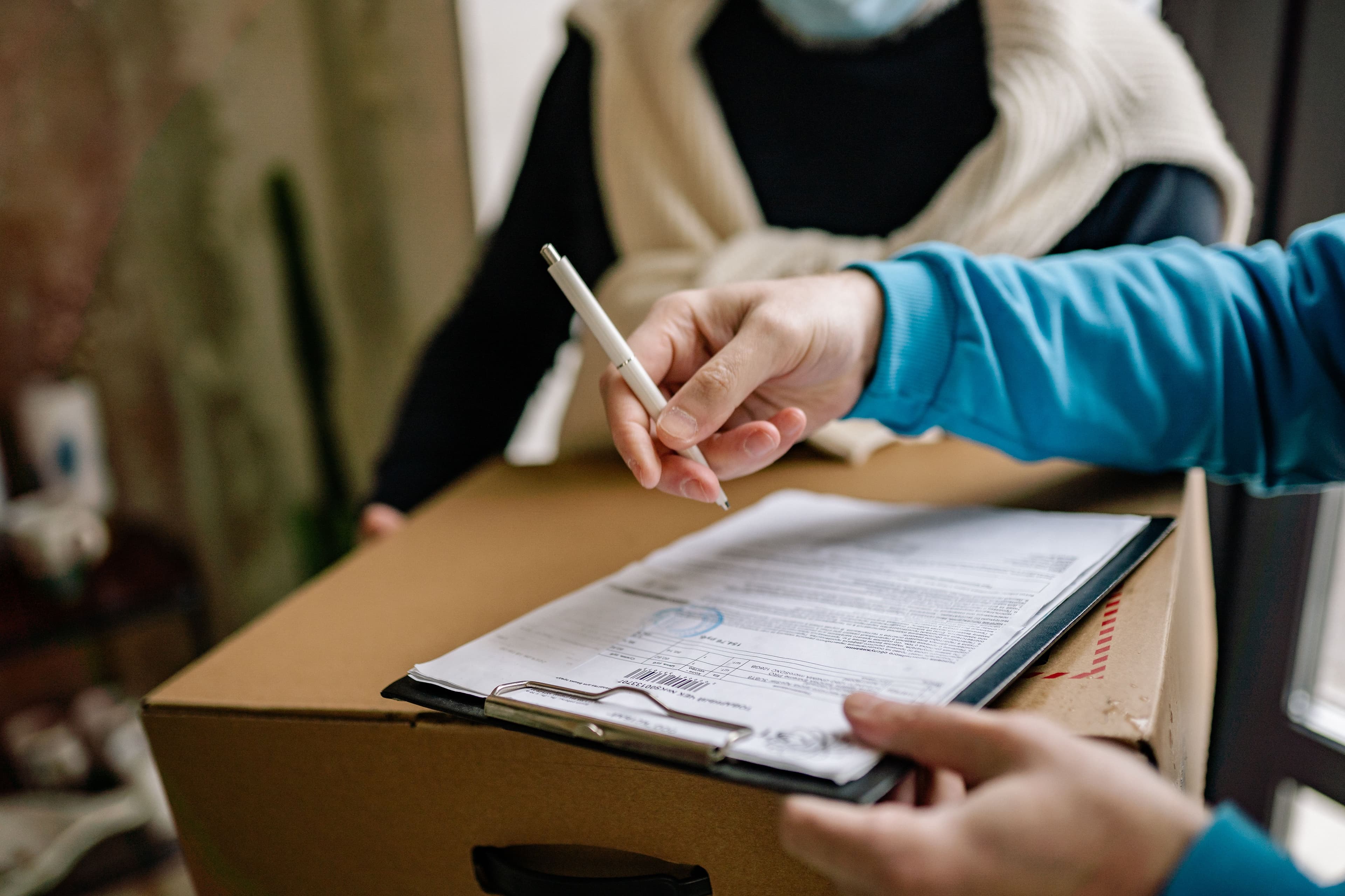 Persona firmando un formulario sobre una caja de cartón
